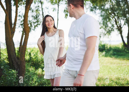 Felice e giovane coppia incinta abbracciando in natura. Momenti romantici Foto Stock