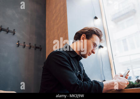 Soft focus.man holding e utilizzo di vendere il telefono.seduti e rilassati sul divano di casa moderna.concetto per i giovani di lavoro del dispositivo mobile Foto Stock