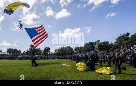 171104-N-RM689-069 Fort Pierce, Fla. (nov. 4, 2017) in pensione Navy SEAL Jim Woods, membro dell'U.S. Navy parachute team, il salto delle rane, presenta la bandiera americana a spettatori come parte di un paracadute di dimostrazione durante la trentaduesima annuale di Navy SEAL Muster e il Festival di Musica ospitato da Marina Nazionale UDT TENUTA-museo. Il salto delle rane sono basati fuori di San Diego e antenna di eseguire dimostrazioni di paracadute intorno alla nazione a sostegno del Naval Special Warfare Marina e del reclutamento del personale. (U.S. Foto di Marina di Massa lo specialista di comunicazione di terza classe Kelsey L. Adams/rilasciato) Foto Stock