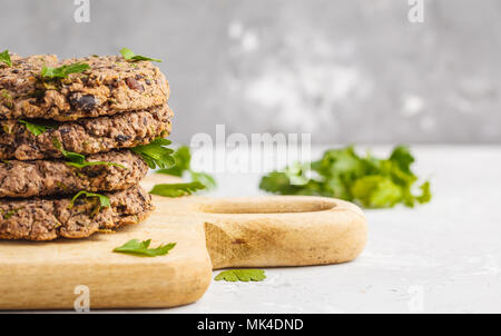 Vegano fagioli hamburger (bistecche) con prezzemolo su una tavola di legno. Sano cibo vegan concetto. Foto Stock