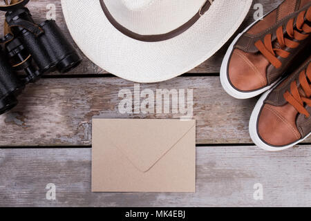 Posta e accessori da viaggio. Scarpe, hat e binocoli. Scrivania in legno sfondo di superficie. Foto Stock