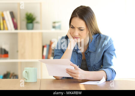 Ritratto di una donna preoccupati la lettura di una lettera su carta su un tavolo a casa Foto Stock