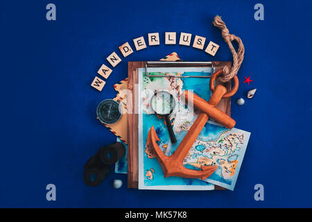 Viaggio di esplorazione e di concetto con mappe ad acquerello, bussola di ancoraggio in legno, binocolo, lente di ingrandimento e Wanderlust scrabble lettere. Appartamento di vacanza giacciono su uno sfondo blu scuro con spazio di copia Foto Stock
