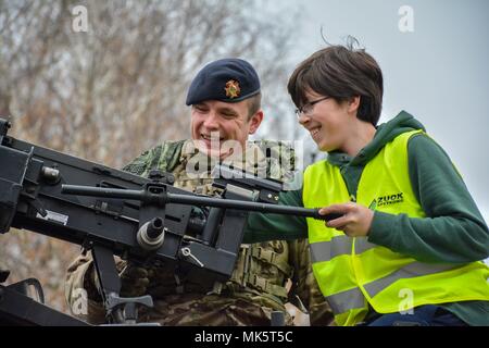 Un soldato dal British luce dragoni assiste uno studente polacco con l'apprendimento circa la sua arma assegnata durante un combattimento display funzionalità per la comunità locale in Orzysz, Polonia, nov. 10, 2017. Foto Stock