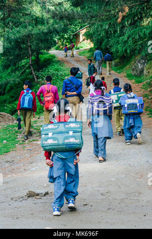 Nagar, Himachal Pradesh, India : schoolchidren indiano a piedi su una ripida strada sterrata sulla loro strada a casa dalla scuola di Naggar. Foto Stock