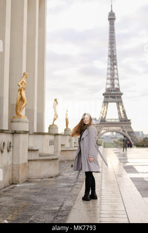 Giovane donna in piedi sulla piazza del Trocadero vicino a statue dorate e la Torre Eiffel. Foto Stock