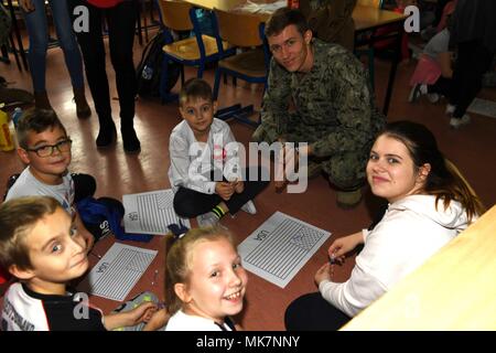 Jezierzyce, Polonia (nov. 14, 2017). Master-at-Arms terza classe Daniel Valleley, assegnato al supporto navale Facility (NSF) Redzikowo, interagisce con gli studenti durante una visita ad una scuola locale in Jezierzyce, Polonia. NSF Redzikowo è la marina del più recente installazione e la prima installazione degli Stati Uniti in Polonia. Le sue operazioni consentono la reattività degli Stati Uniti e delle forze alleate a sostegno del Navy regione Europa, Africa, Asia sud-ovest (NAVEURAFSWA) missione di fornire i servizi per la flotta, Fighter, e famiglia. (U.S. Navy foto di Lt. Maria Sanford/rilasciato) Foto Stock