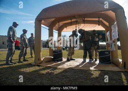 Stati Uniti Avieri simulare decontaminare un pilota mentre ispezione ala ai membri del team di guardare durante il primo rapido pronto donnola presso Shaw Air Force Base, South Carolina, nov. 16, 2017. La 55th Fighter Squadron di equipaggi di apparecchiature di volo aviatori correva una linea di decontaminazione, in seguito a varie procedure per estrarre con sicurezza un pilota al di fuori della loro marcia dopo simulazione chimici, biologici, radiologici e nucleari condizioni. (U.S. Air Force foto di Airman 1. classe destinatario Sweeney) Foto Stock