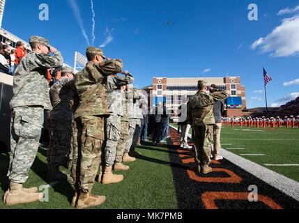 Membri dell esercito e Air Force ROTC distacchi in Oklahoma State University salutare la bandiera americana durante l'Inno Nazionale nov. 18, 2017, a Boone Pickens Stadium, Oklahoma State University, Stillwater, Oklahoma. La riserva degli ufficiali di corpo Training Program è stato creato formalmente nel 1916 e produce quasi il 30 percento dei funzionari miltary ogni anno. (U.S. Air Force foto di Airman Zachary guarire) Foto Stock