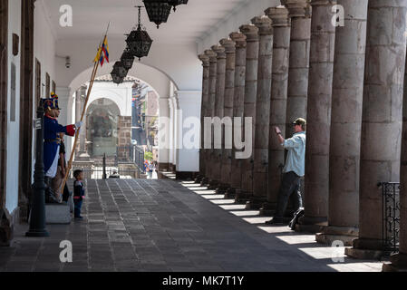 Turistica prendendo una foto di una famiglia in posa con la guardia presidenziale presso il Palazzo Carondelet nel centro storico della città di Quito, Ecuador. Foto Stock