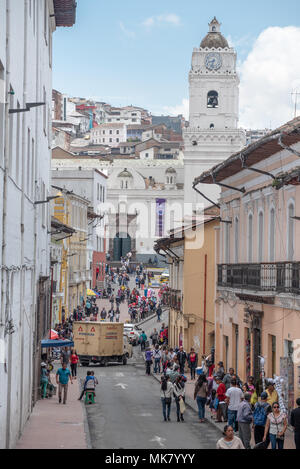 Pedoni in una stradina nel centro storico della città di Quito, Ecuador. La Merced Chiesa è in background. Foto Stock