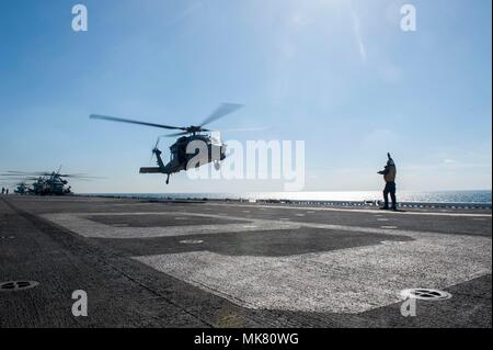 171125-N-ZS023-029 GOLFO ARABICO (nov. 25, 2017) di aviazione di Boatswain Mate (movimentazione) terza classe Diefendorf Giosuè, nativo di Bremerton, nello Stato di Washington, assegnato al dipartimento dell'aria a bordo dell'assalto anfibio nave USS America (LHA 6), segnali un MH-60S Sea Hawk elicottero assegnato al "Jolly" di elicottero di mare squadrone di combattimento (HSC) 23 sul ponte di volo. L'America è l'ammiraglia per l'America anfibio gruppo pronto e, con l'avviato xv MEU, è distribuito negli Stati Uniti Quinta Flotta area di operazioni a sostegno della sicurezza marittima operazioni destinate a rassicurare gli alleati e partner e pre Foto Stock