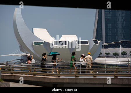 I turisti camminano sul ponte contro il magnifico sfondo del Museo della Scienza dell'Arte e del resort integrato Marina Bay Sands, Singapore Foto Stock