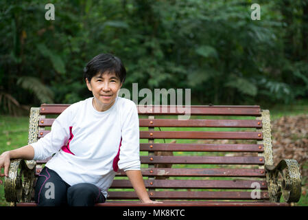 Senior donna relax su una panchina nel parco Foto Stock