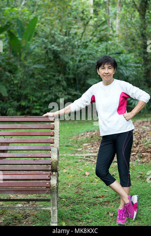 Senior donna relax su una panchina nel parco Foto Stock