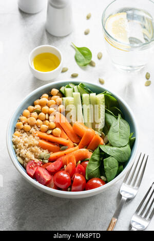 Alimentando la ciotola di buddha con la quinoa, baby carote, spinaci, cetriolo, ceci e pomodori sul tavolo bianco. Mangiare sano, uno stile di vita sano, dieta Foto Stock