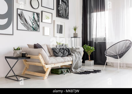 Poltrona accanto al divano in legno in contrasto living room interior con Galleria di manifesti Foto Stock