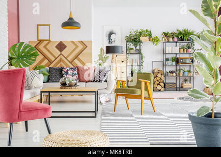 Boho living room interior con piante, retro poltrona e divano con cuscini colorati Foto Stock