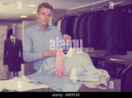 Acquirente maschio in camicia scegliendo cravatta e camicia nel negozio di abbigliamento Foto Stock
