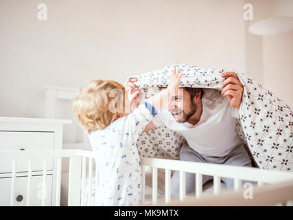 Padre con un bimbo piccolo ragazzo divertendosi in camera da letto a casa prima di andare a dormire. Foto Stock