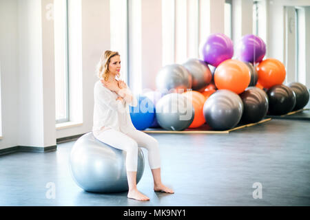 Giovane donna facendo esercizio con una fitball in una palestra. Foto Stock