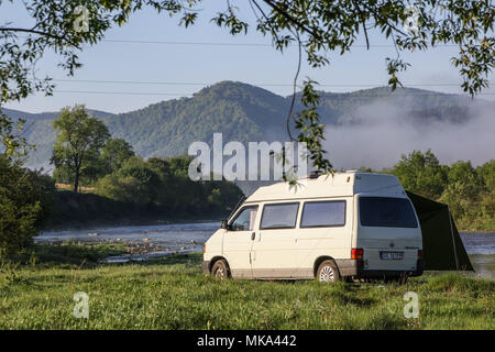 Van - lifers in piedi il loro Volkswagen Transporter T4 camper sulla Stryi (Stryj) banca del fiume sono visibili nelle montagne dei Carpazi (Besikd) in vill Foto Stock