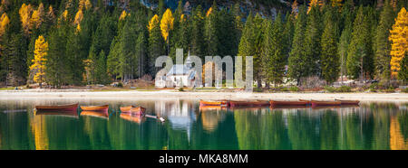 Bellissima vista di legno tradizionali barche a remi e storica cappella riflettendo in spettacolare Lago di Braies nelle Dolomiti, Alto Adige, Italia Foto Stock