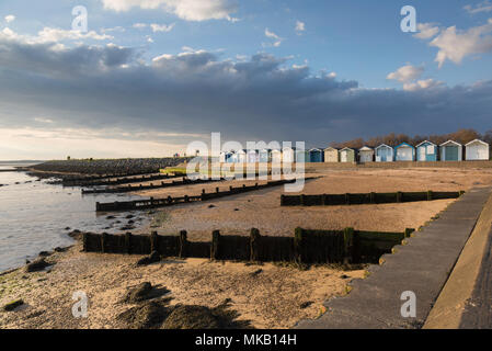 Luce brillante sulla spiaggia di capanne a Brightlingsea, Essex, Regno Unito. Foto Stock