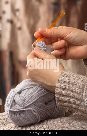 Le mani della donna maglia con ferro da uncinetto e filo grigio Foto Stock