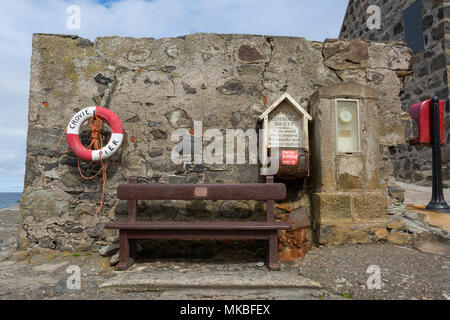 Sedile, lifebelt, barometro e casella di donazione presso il molo, Crovie, Aberdeenshire, Scotland, Regno Unito Foto Stock