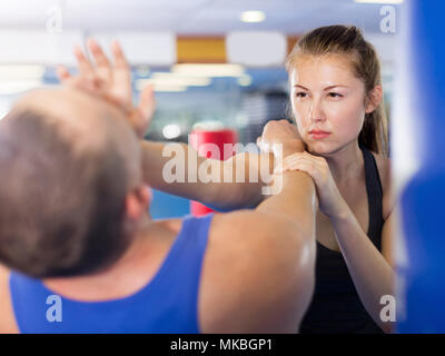 La ragazza e il suo trainer sono la pratica punzoni sul self-defence corso nella casella palestra Foto Stock