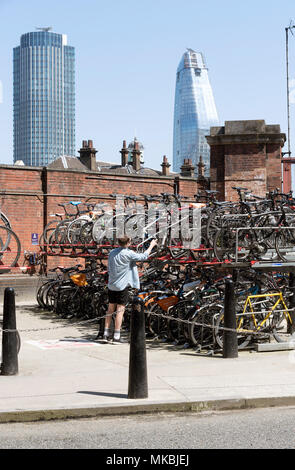 La stazione di Waterloo, Londra UK. 2018. Due tier parcheggio per i clienti di parcheggiare i loro cicli. Un maschio di clienti parcheggio la sua bici Foto Stock