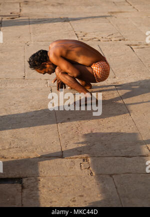 Sulle rive del fiume Gange a Varanasi centinaia di persone può essere visto fare yoga come esercizio, questo signore era solo uno dei molti partecipanti Foto Stock