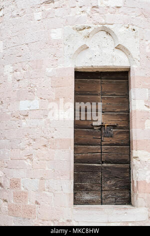 Una vecchia porta di legno con un antico muro di pietra Foto Stock