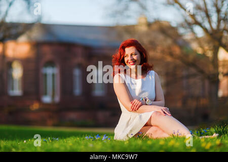 Ritratto di una bella donna sorridente che siede sul prato Foto Stock