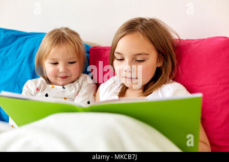 Bambine o sorelle libro di lettura a letto Foto Stock