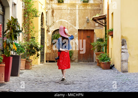 Vista posteriore del turista donna in piedi e tenendo hat a Trastevere a Roma, Italia. Foto Stock