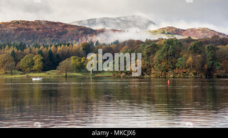 La nebbia sale dal bosco in autunno di colore a Ambleside sul lago di Windermere, sotto Wetherlam montagna in Langdale in Inghilterra del Lake District National Pa Foto Stock