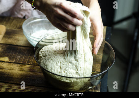 Impasto ormeggiata sulla tavola di legno, tradizionale pretzel preparazione, baker rendendo la pasta di pane nel forno. mani giocate con farina e pasta. Foto Stock