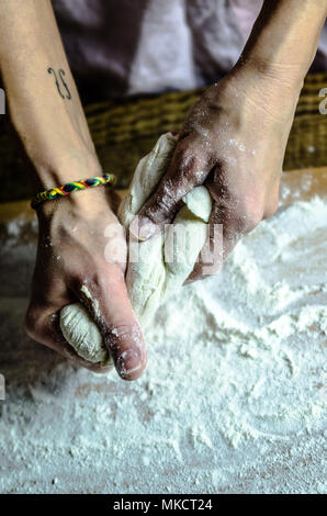 Impasto ormeggiata sulla tavola di legno, tradizionale pretzel preparazione, baker rendendo la pasta di pane nel forno. mani giocate con farina e pasta. Foto Stock