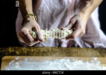 Impasto ormeggiata sulla tavola di legno, tradizionale pretzel preparazione, baker rendendo la pasta di pane nel forno. mani giocate con farina e pasta. Foto Stock