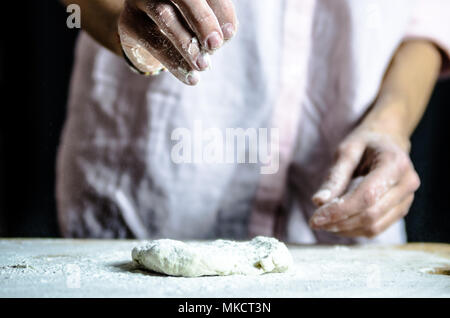 Impasto ormeggiata sulla tavola di legno, tradizionale pretzel preparazione, baker rendendo la pasta di pane nel forno. mani giocate con farina e pasta. Foto Stock