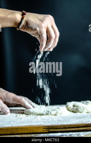 Impasto ormeggiata sulla tavola di legno, tradizionale pretzel preparazione, baker rendendo la pasta di pane nel forno. mani giocate con farina e pasta. Foto Stock