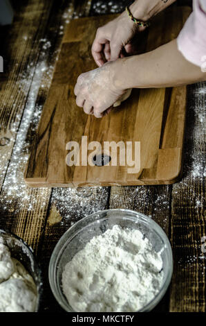 Impasto ormeggiata sulla tavola di legno, tradizionale pretzel preparazione, baker rendendo la pasta di pane nel forno. mani giocate con farina e pasta. Foto Stock