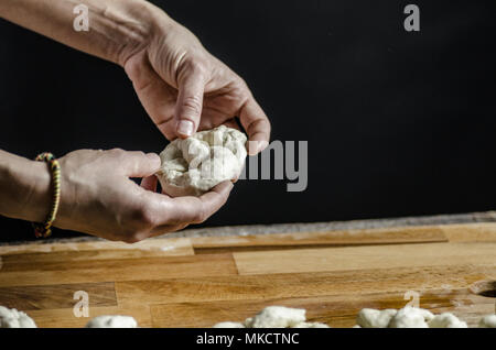 Impasto ormeggiata sulla tavola di legno, tradizionale pretzel preparazione, baker rendendo la pasta di pane nel forno. mani giocate con farina e pasta. Foto Stock