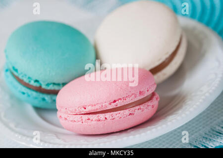 Tre amaretti di diversi colori e gusti diversi in una piastra bianca, vista dall'alto. Romantica mattina, dono per diletto. La colazione sul Valentin, madri, giornata della donna. Sfondo di gara Foto Stock