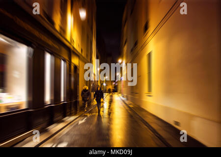 Sfocate immagini di movimento delle persone che camminano sulla strada di notte a Parigi. Foto Stock