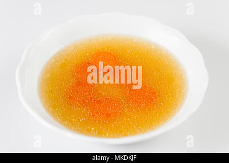 Chiara brodo di manzo con fette di carota. Brodo di osso. Bouillon in bianco recipiente.isolato su bianco. Foto Stock