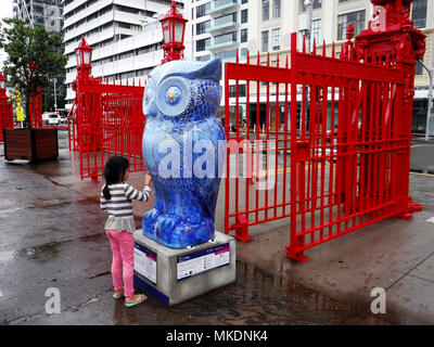 Giovane ragazza asiatica toccando il gufo statua in Auckland Nuova Zelanda Foto Stock