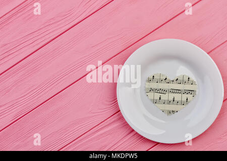 Cuori di carta sulla piastra bianca. Cuori di carta con note musicali e clef bianco sulla piastra di porcellana, copia dello spazio. Foto Stock